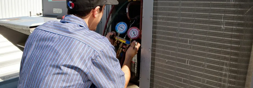 HVAC technician servicing a condenser unit in Brookhaven